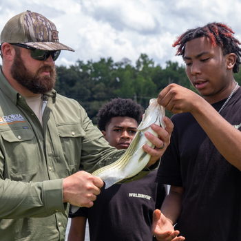WRD Hunter Roop teaches camper to hold fish