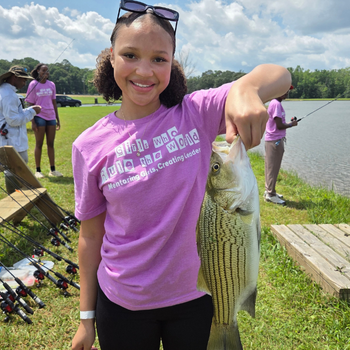 Girls mentoring participant holds a hybrid striped bass