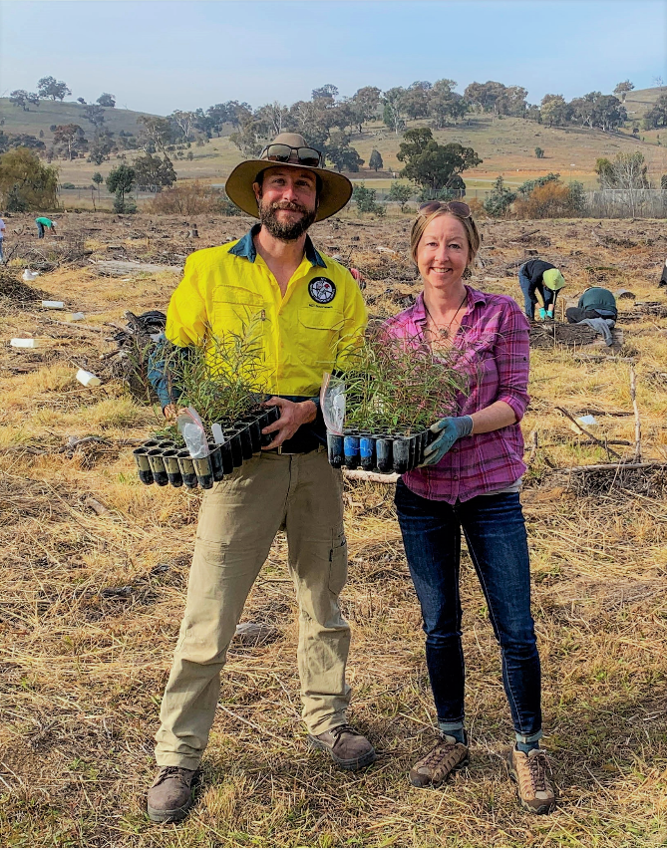 Helen Bothwell stands in a field with another scientist