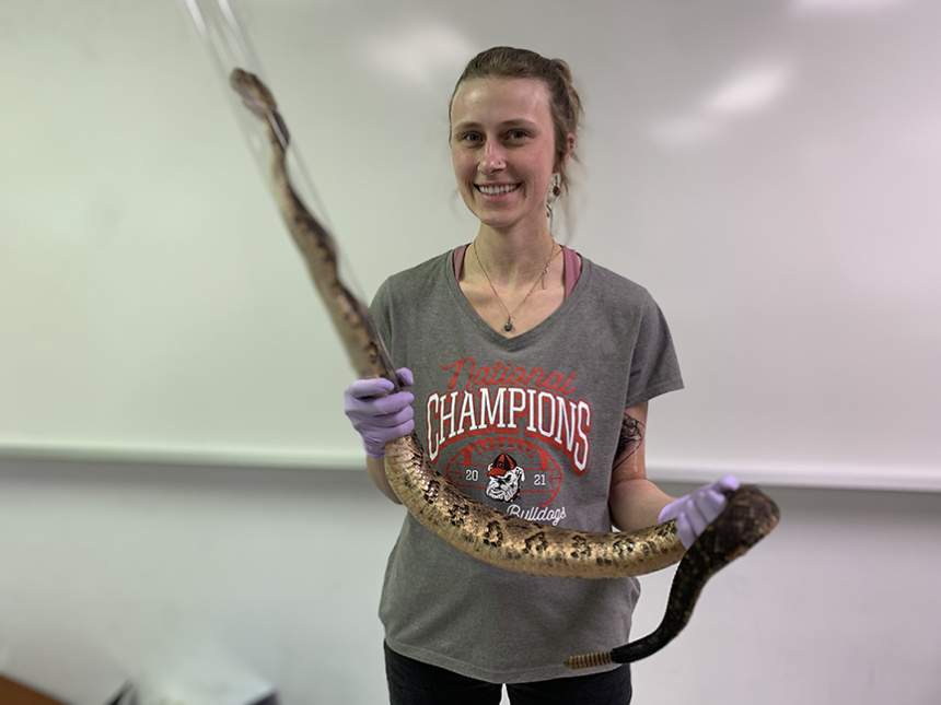 Corinna Hazelrig holds a snake in a plastic tube