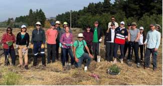 Members of the lab stand in a straw-covered field