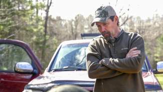 Mike Chamberlain leans on hood of field truck