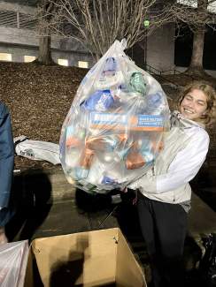 A student holds up a bag of recycling collected at a recent baseball game.