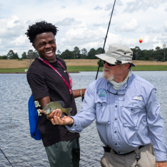 Jay Shelton shows camper how to hold fish properly