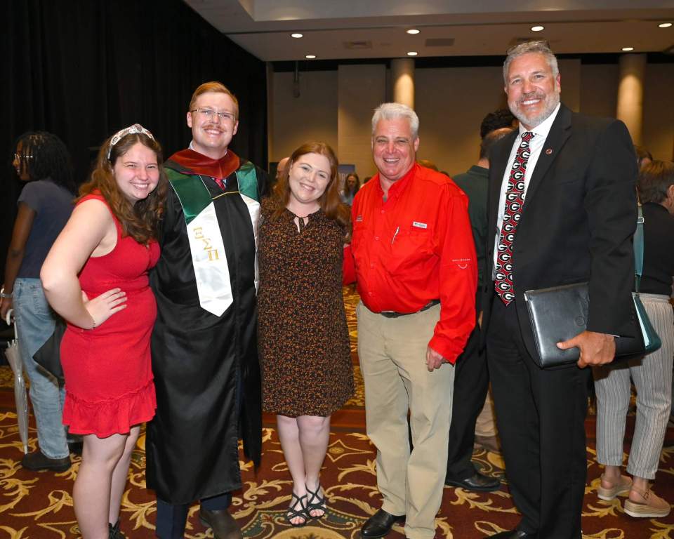 Master's student Jack Derochers stands for a photo with family members and Robert Bringolf, associate dean for academic affairs