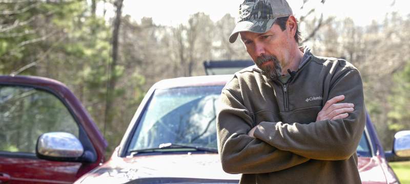 Mike Chamberlain leans on hood of field truck