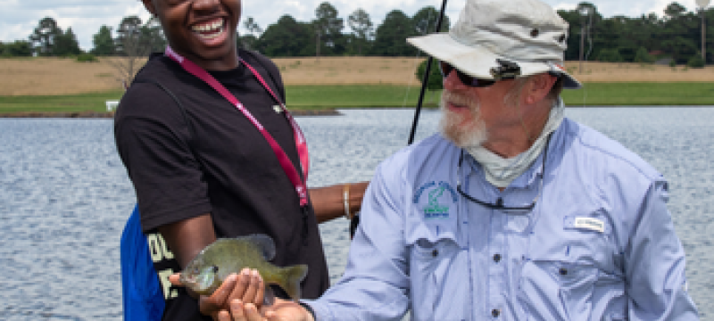 Jay Shelton shows camper how to hold fish properly