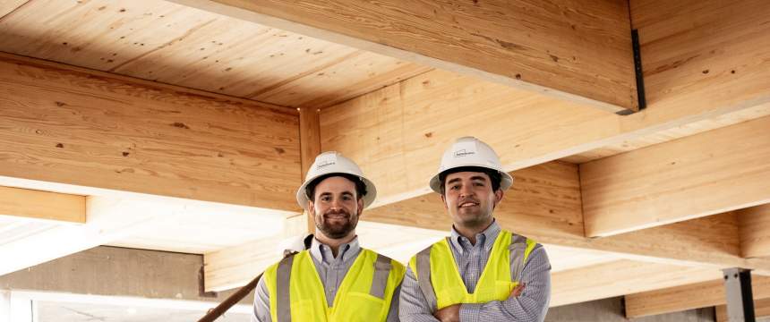 Andrew Carroll and Henry Morris stand among mass timber beams