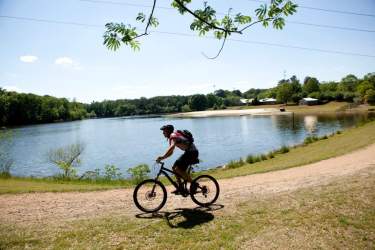 A man rides a bike past Lake Herrick
