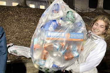 A student holds up a bag of recycling collected at a recent baseball game.