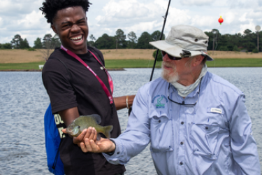 Jay Shelton shows camper how to hold fish properly