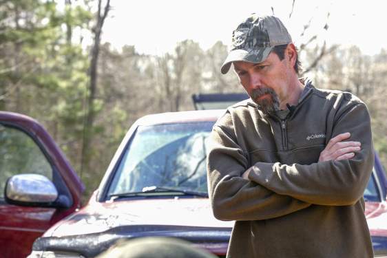 Mike Chamberlain leans on hood of field truck