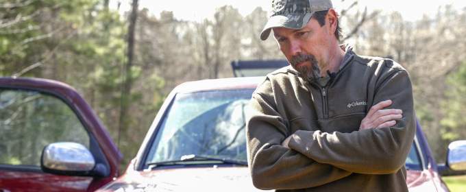 Mike Chamberlain leans on hood of field truck