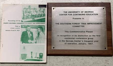 A booklet and a commemorative plaque acknowledging the Southern Forest Tree Improvement Committee for its distinction in 1957, displayed side by side on a table.